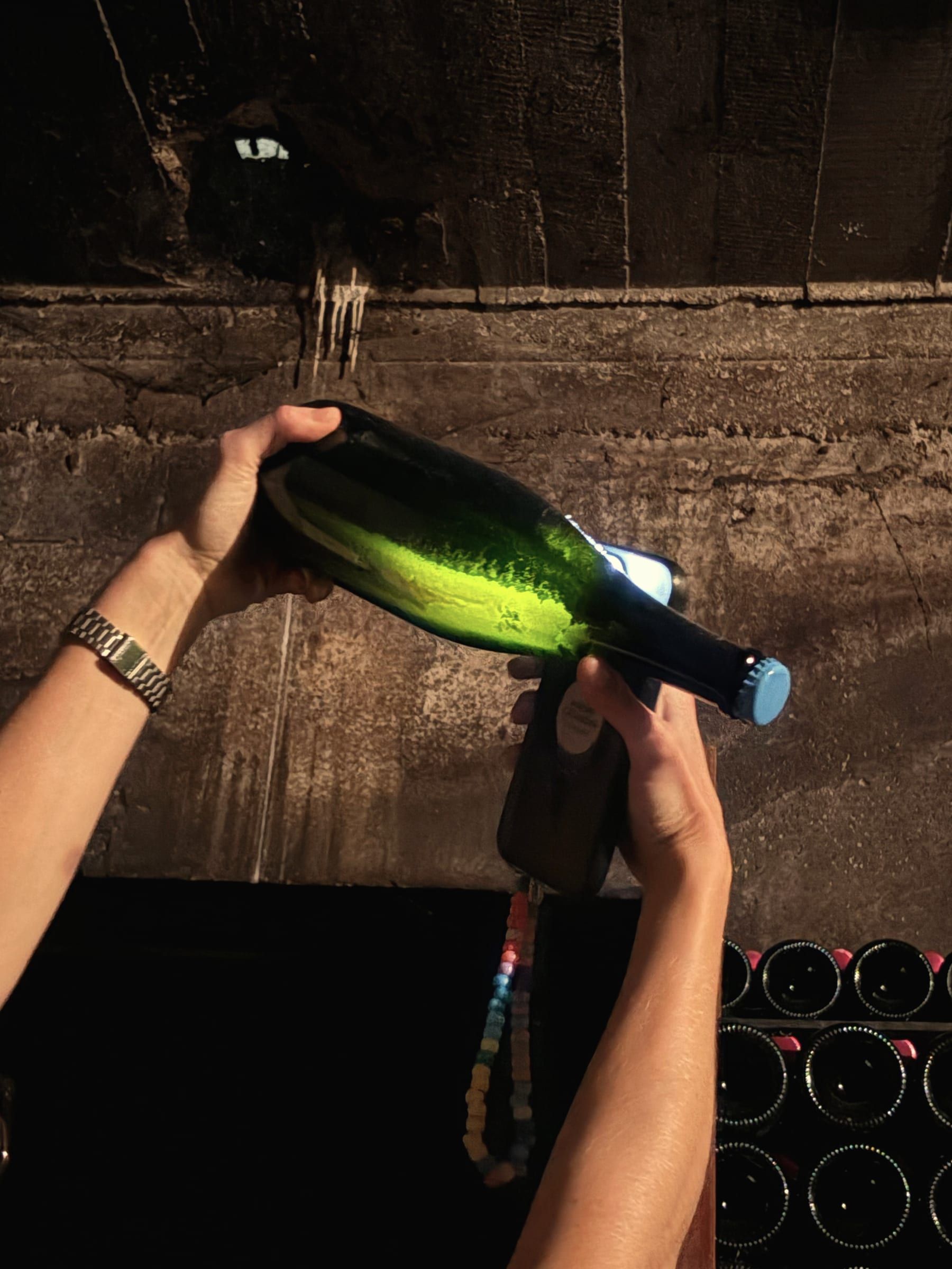 Une bouteille regardée à la lumière, dans une cave creusée dans la roche