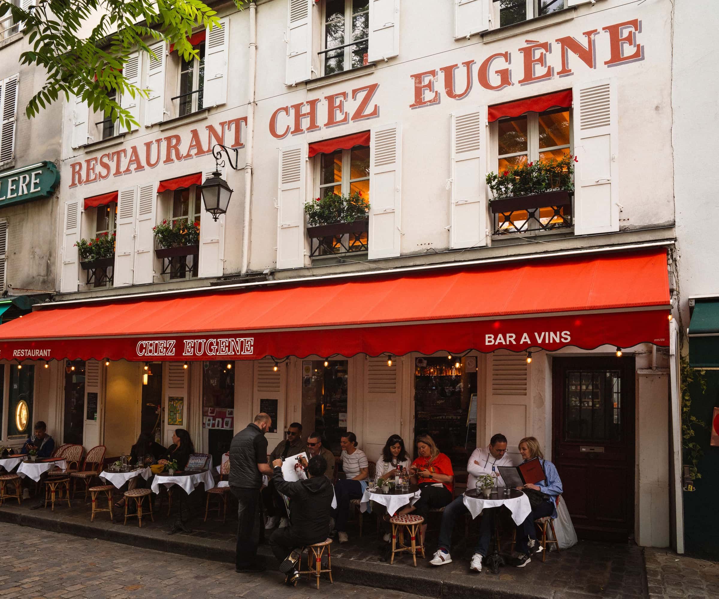 The front of Chez Eugène, the red awning and a full terrace