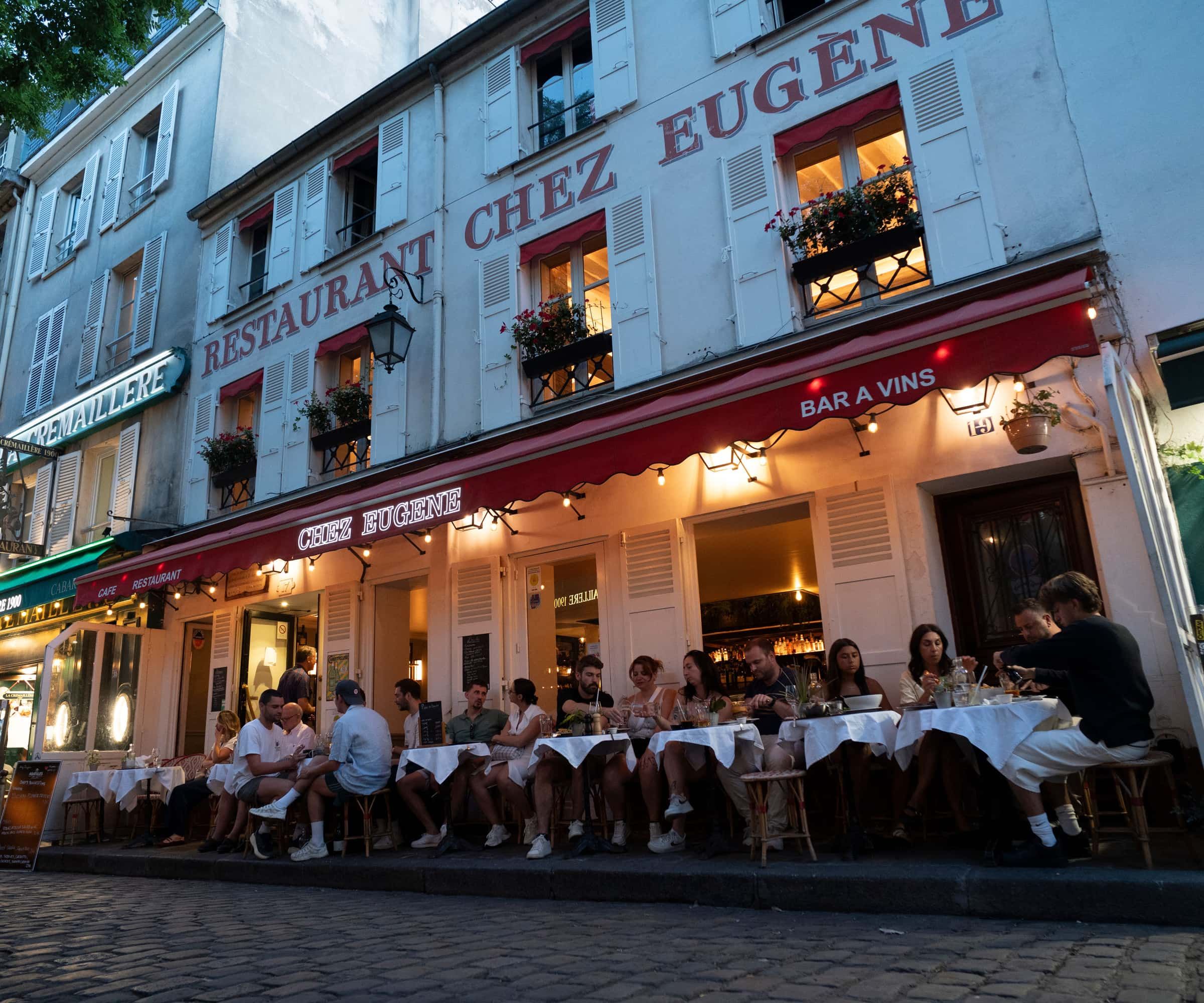 La façade de Chez Eugène le soir, place du Tertre à Montmartre, terrasse pleine