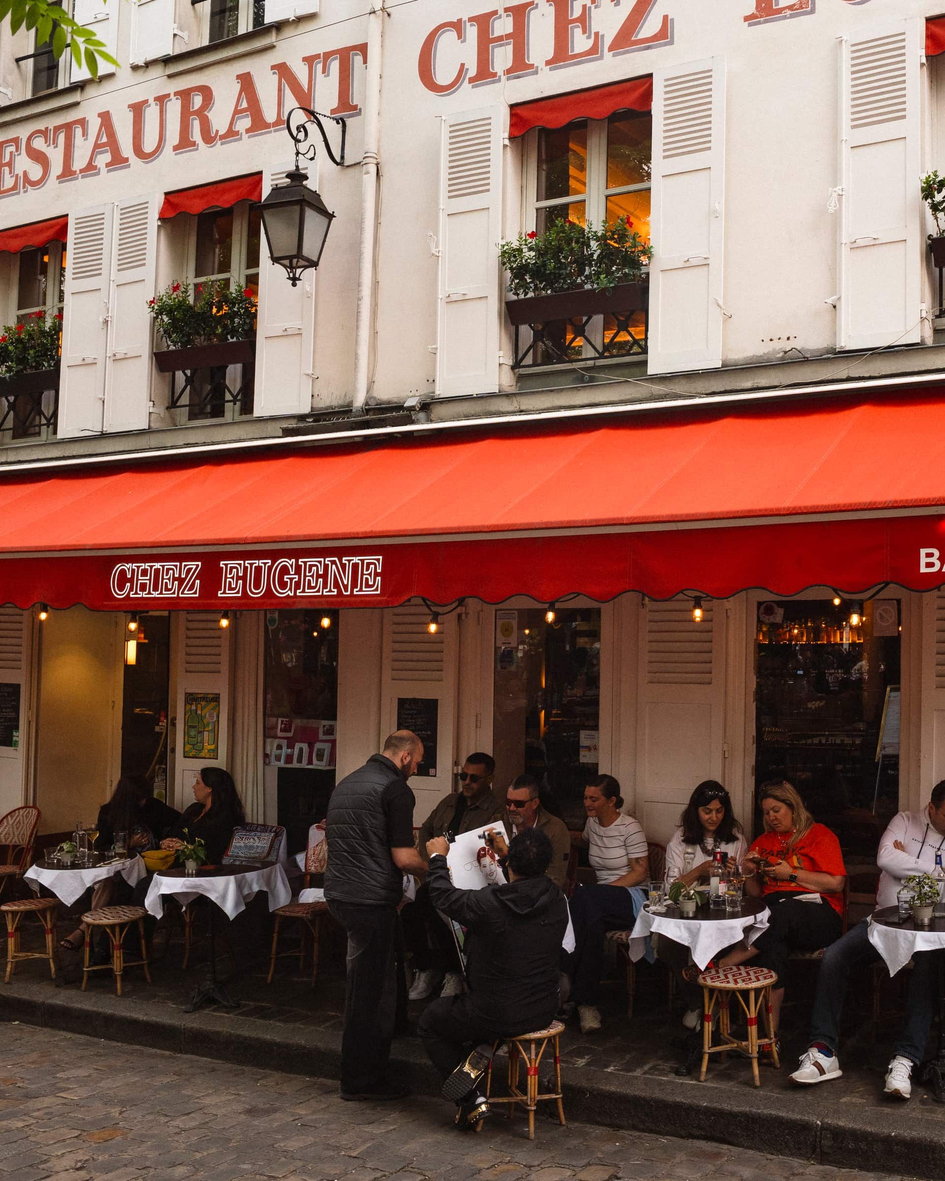 La façade de Chez Eugène et son store rouge, sur la Place du Tertre