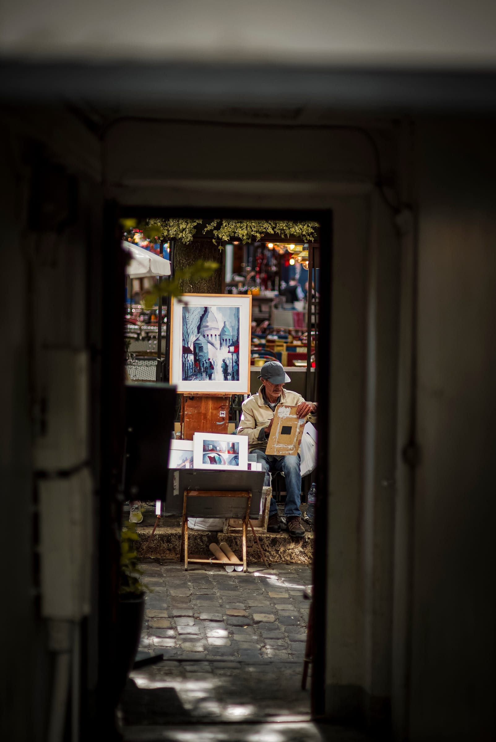 Par une porte ouverte, un peintre de la Place du Tertre