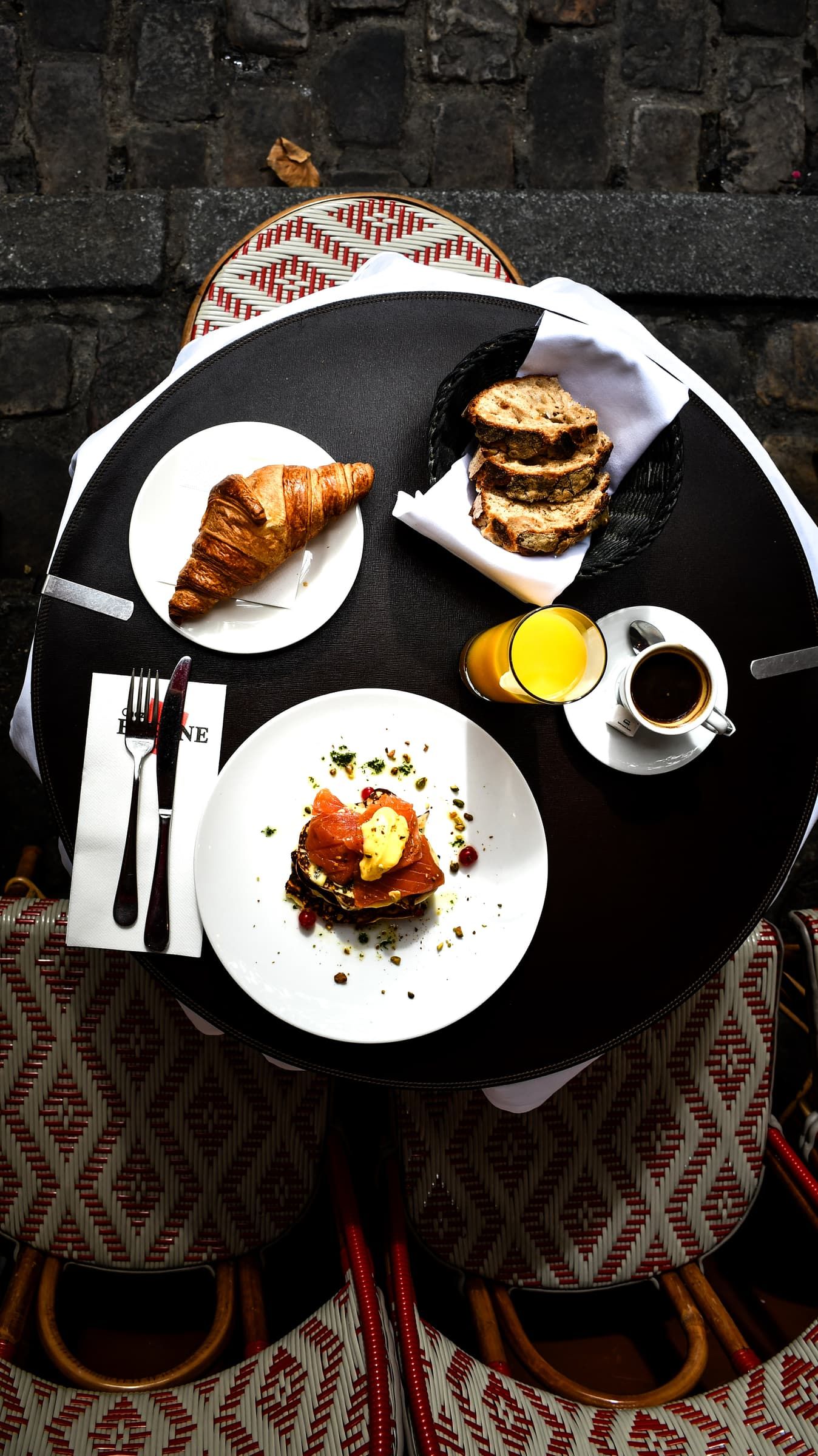 Petit-déjeuner à Montmartre : croissant, œufs, pain grillé, jus d'orange et café sur une table de Chez Eugène, place du Tertre