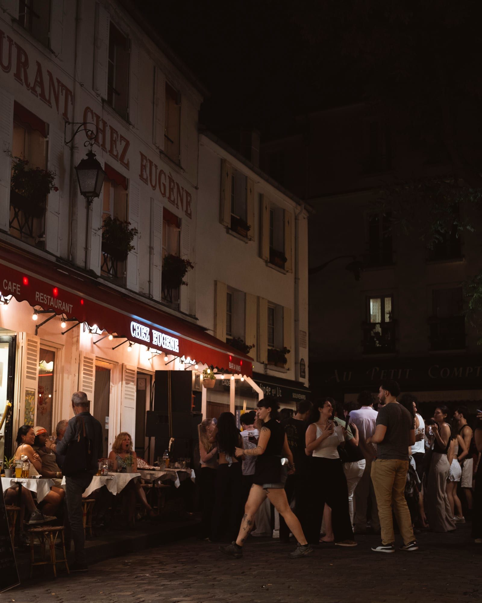 La façade de Chez Eugène la nuit, du monde qui reste sur la Place