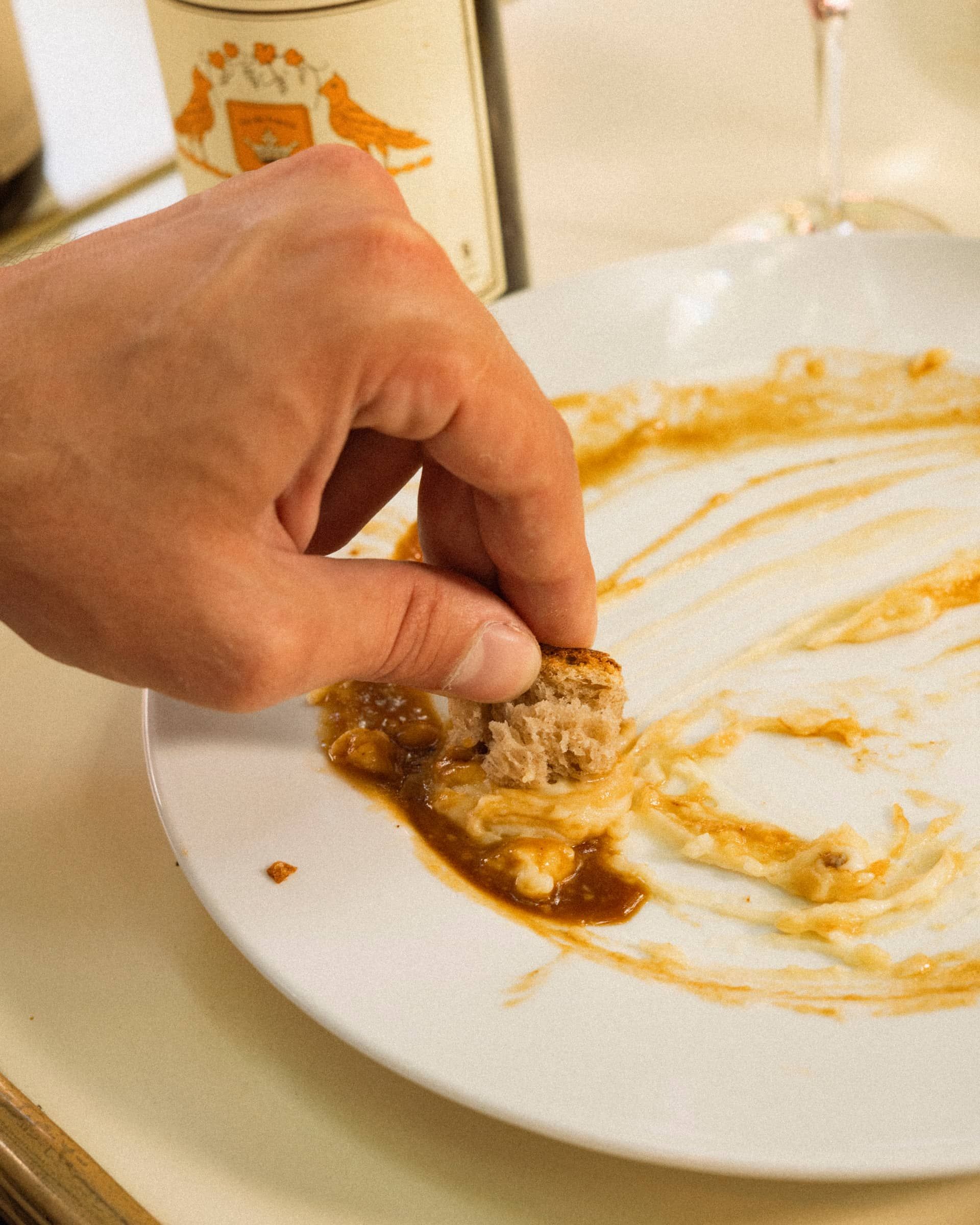 A hand mopping the plate with a piece of bread