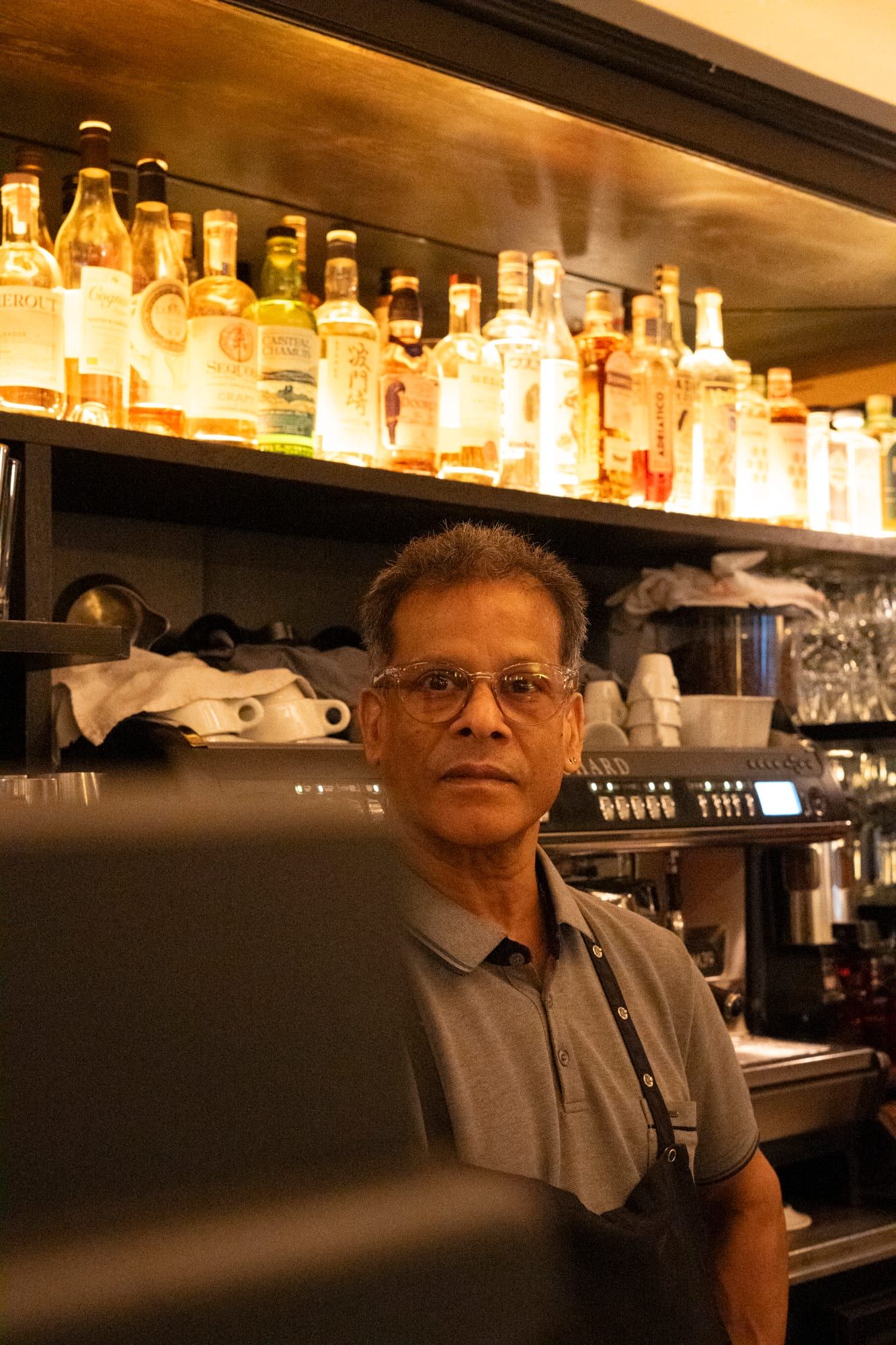 Derrière le comptoir, devant les bouteilles